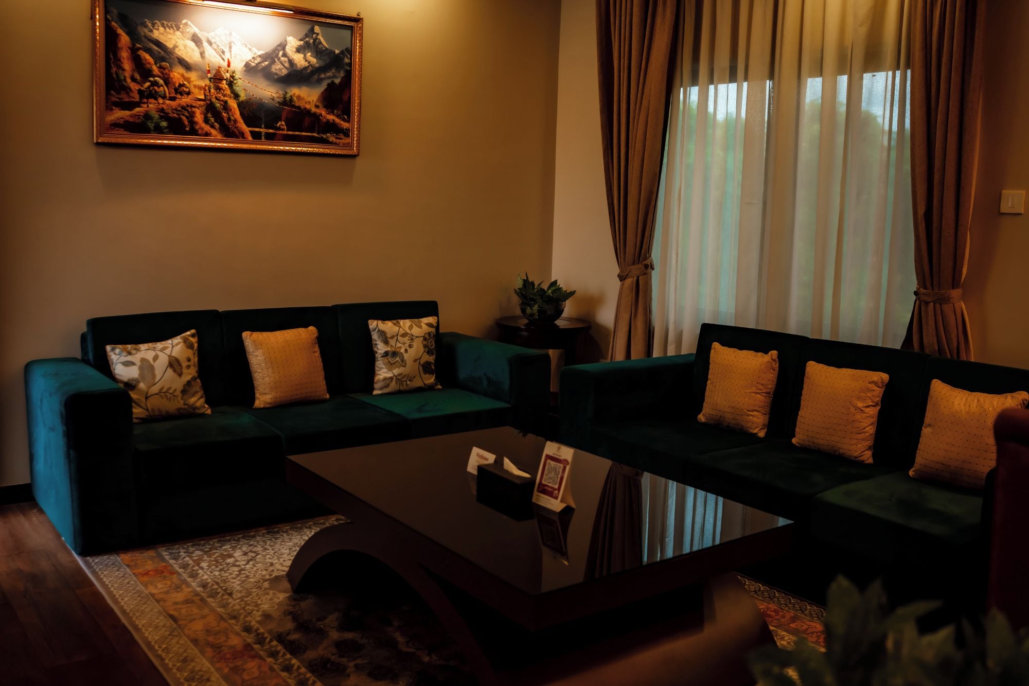 A living room with a sofa set, a coffee table, a painting on the wall, and a window with curtains.