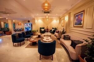 Un hall de hotel con una zona de estar, un mostrador de recepción y una escalera que conduce a los pisos superiores.