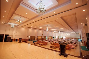 A spacious hall with tiered seating, chandeliers, and a podium.