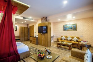 Una habitación de hotel con una cama, un televisor, un sofá, una mesita de centro y un cuadro en la pared.