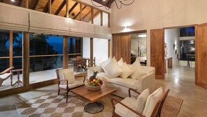 A spacious living area with a high ceiling, large windows, and a chandelier. - Kings Pavilion (Kandy)