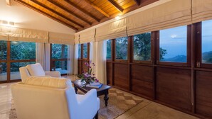 A spacious room with a high ceiling, large windows, and a view of the outdoors. - Kings Pavilion (Kandy)
