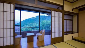 A traditional Japanese room with tatami flooring, sliding doors, and a view of a forested mountain. - Yufuin Onsen Yufuin Nanairo No Kaze (Yufu)
