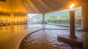 A hot spring area with a large pool, seating area, and a view of greenery outside. - Yufuin Onsen Yufuin Nanairo No Kaze (Yufu)