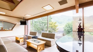 A modern interior with a glass table, beige sofas, and a view of mountains through large windows. - Yufuin Onsen Yufuin Nanairo No Kaze (Yufu)