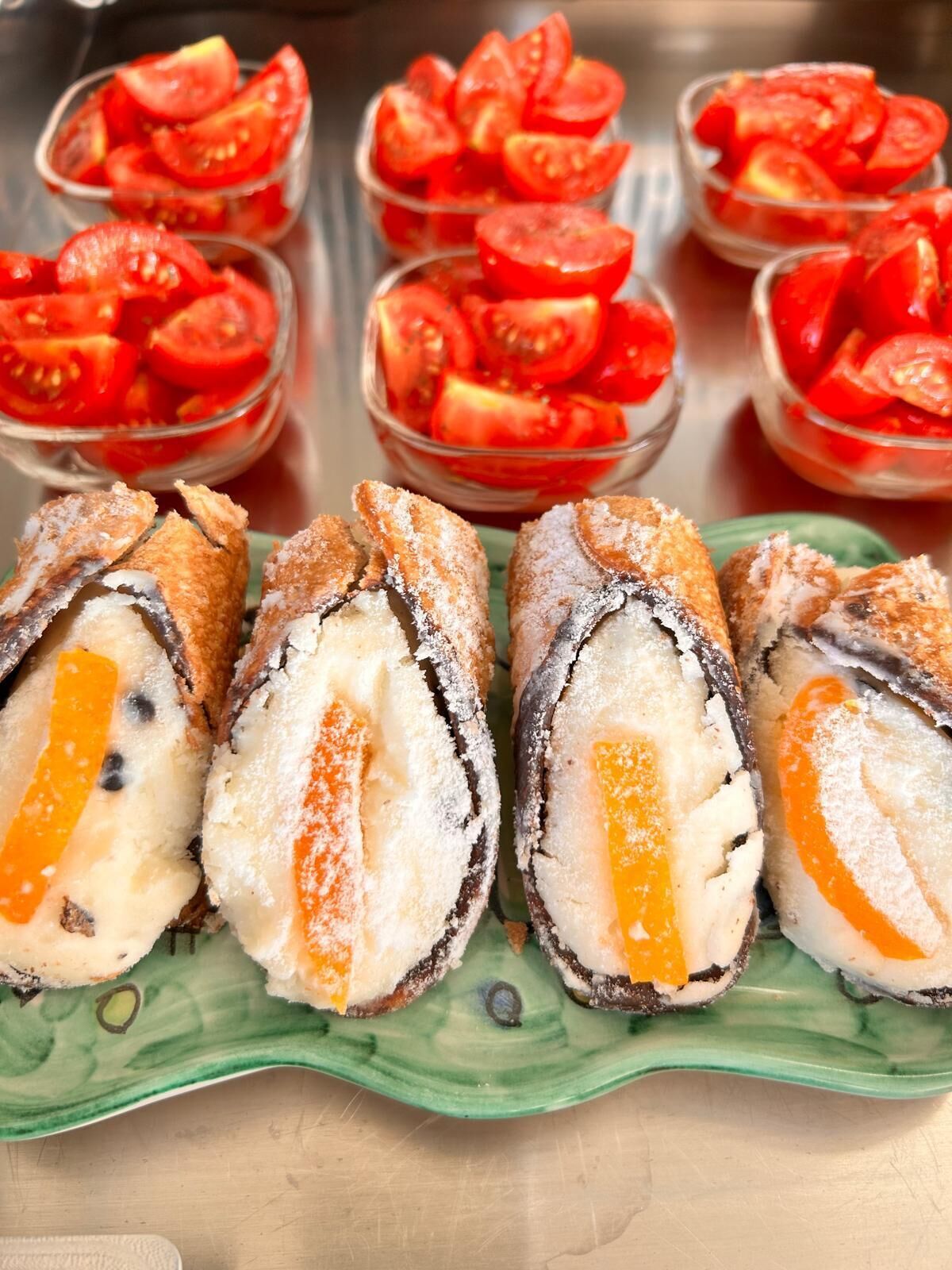Une assiette avec des tomates en tranches et un plat vert en forme de feuille contenant un dessert enroulé.