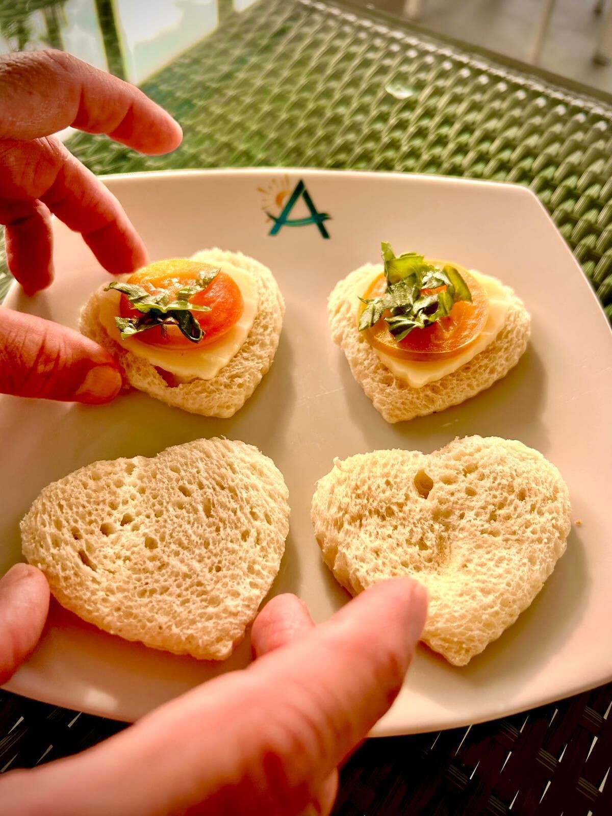 Ein Teller mit vier belegten Broten und zwei Brotscheiben auf einem Tisch.