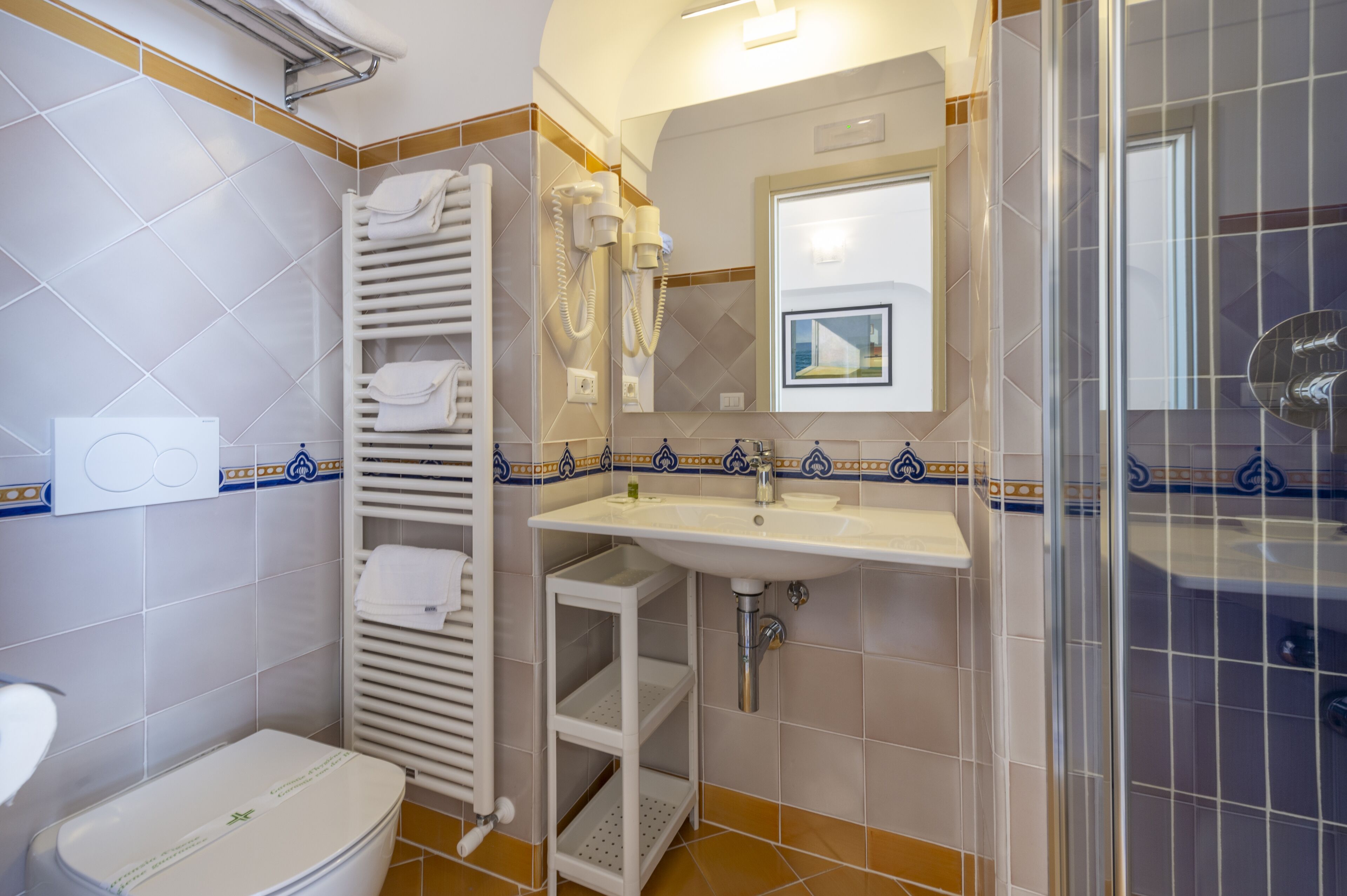 Egy fürdőszoba, amelyben WC, mosdókagyló és zuhanyzó található.