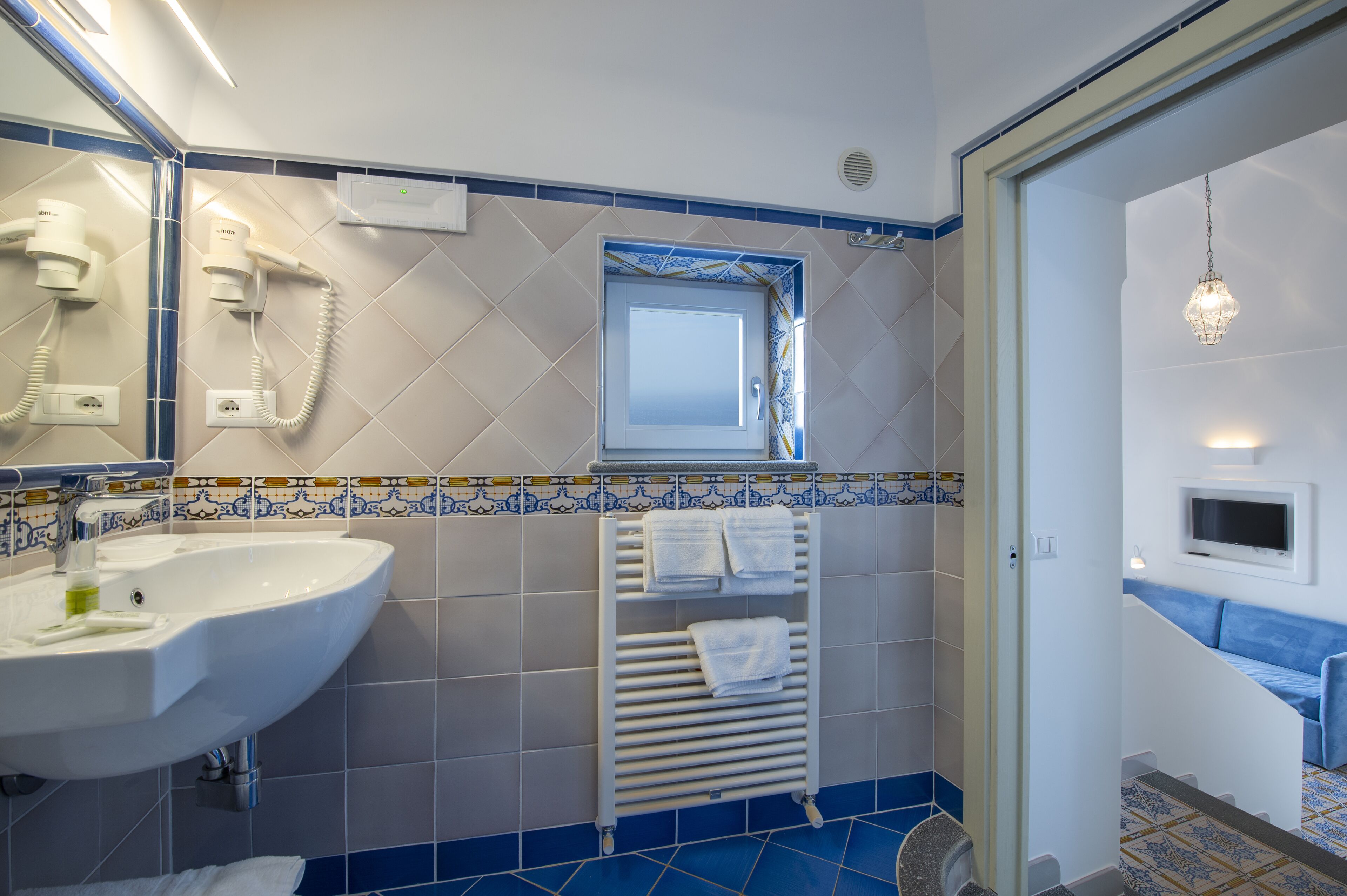 Casa de banho com lavatório, secador de cabelo, porta-toalhas e janela.