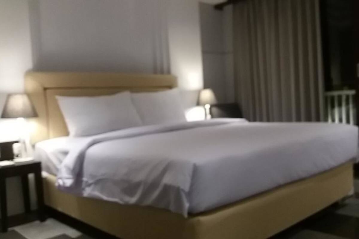 A hotel room with a bed, two bedside tables, and a nightstand.