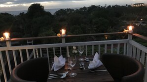 Una mesa para dos con velas, un vaso de agua y una copa de vino en un balcón con vistas panorámicas.