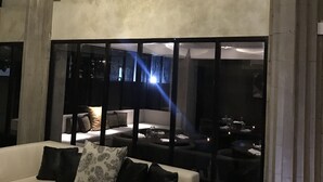 Un interior moderno con un sofá blanco, una pared decorativa con motivos florales y una zona de estar con vistas amplias a través de grandes ventanales.