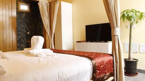 Una habitación de hotel con una cama, televisión, planta en maceta y ventana.