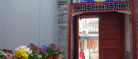 Un estrecho callejón con una puerta tradicional roja y un acceso azul y dorado decorativo.