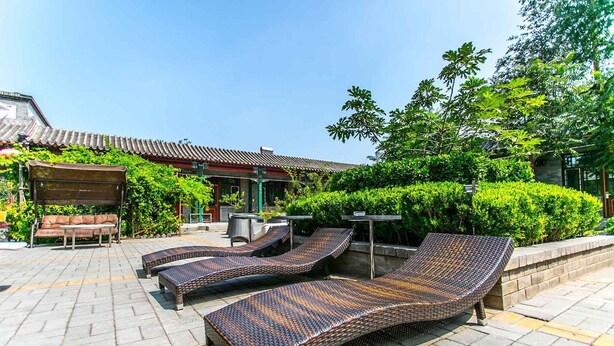 Un edificio de estilo tradicional con techo de tejas y un patio con sillones y un banco.