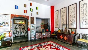 Un interior tradicional con un pilar rojo, caligrafía y una alfombra floral.