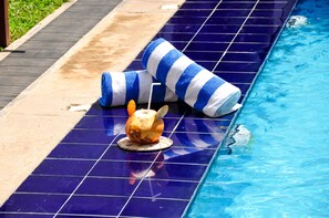 Un espace aménagé au bord de la piscine, doté d’un sol carrelé, d’une chaise longue et d’un élément décoratif.