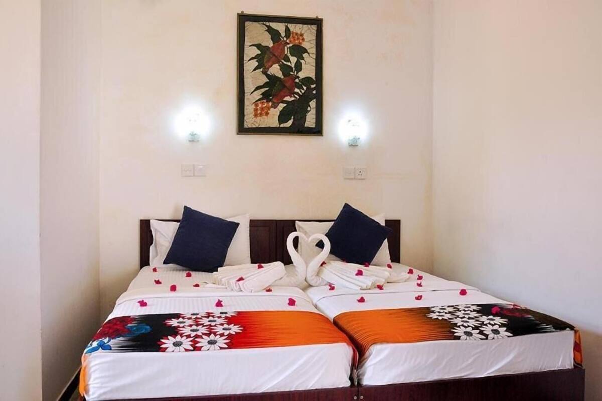 A double bed with a floral bedspread, two pillows, and a heart-shaped towel arrangement.