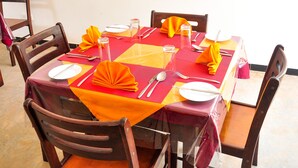 A dining table set with yellow napkins, silverware, and clear glassware. - Sea Breeze (Mirissa)