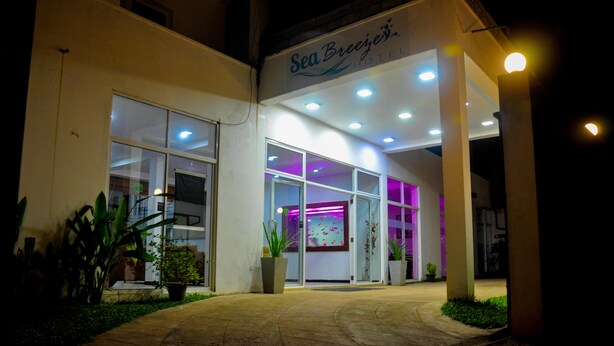 The exterior of Sea Breeze Hotel with a well-lit entrance, large windows, and potted plants. - Sea Breeze (Mirissa)