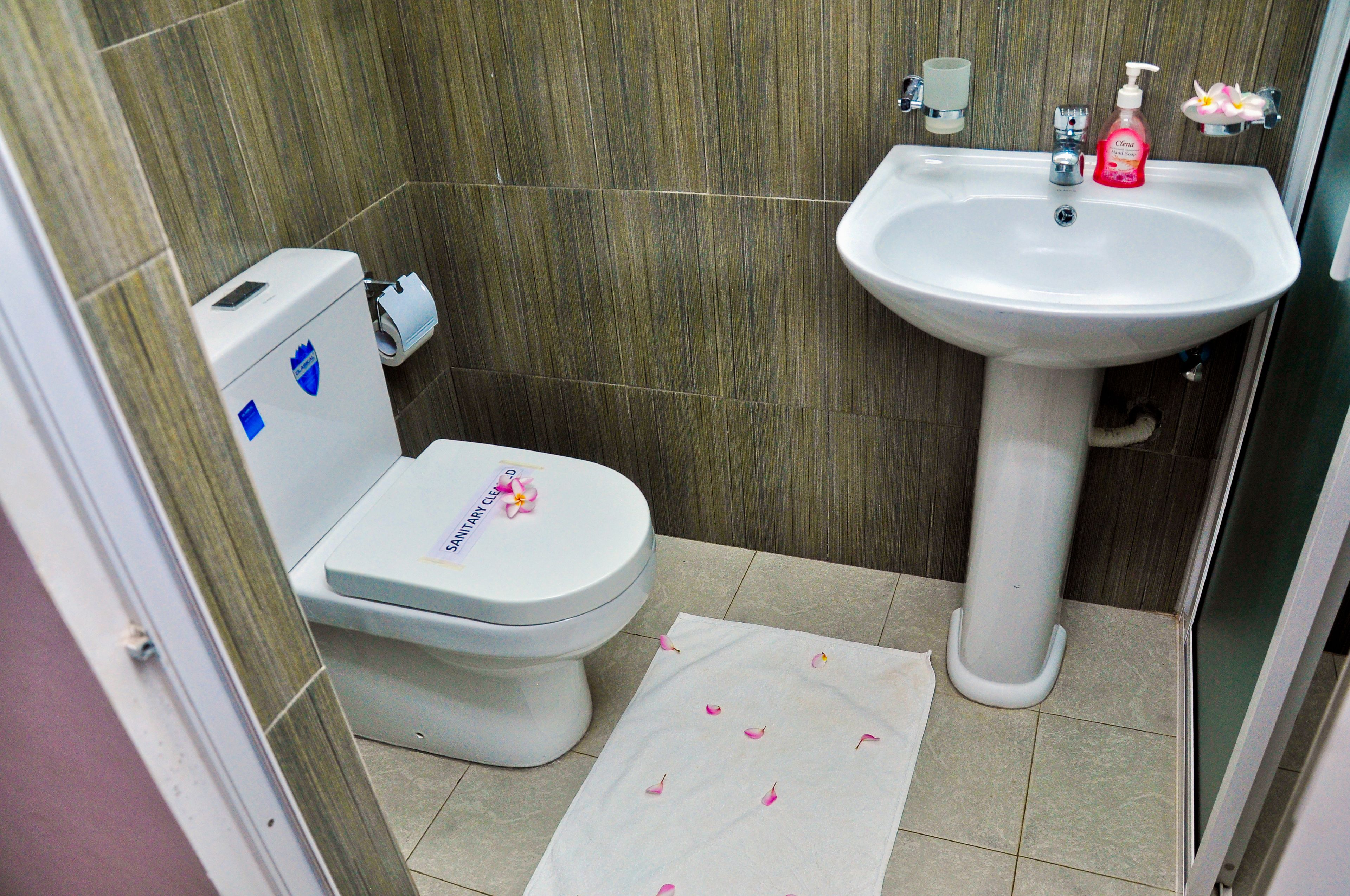 Un baño con inodoro, lavamanos y soporte para papel higiénico.