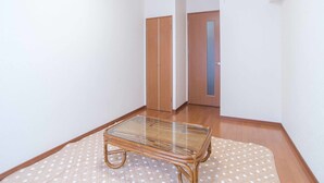 Een kamer met een tafel met glazen blad, houten vloer en een gestreept vloerkleed.