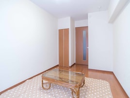Una habitación con una mesa de vidrio, piso de madera y un tapete con estampado de lunares.