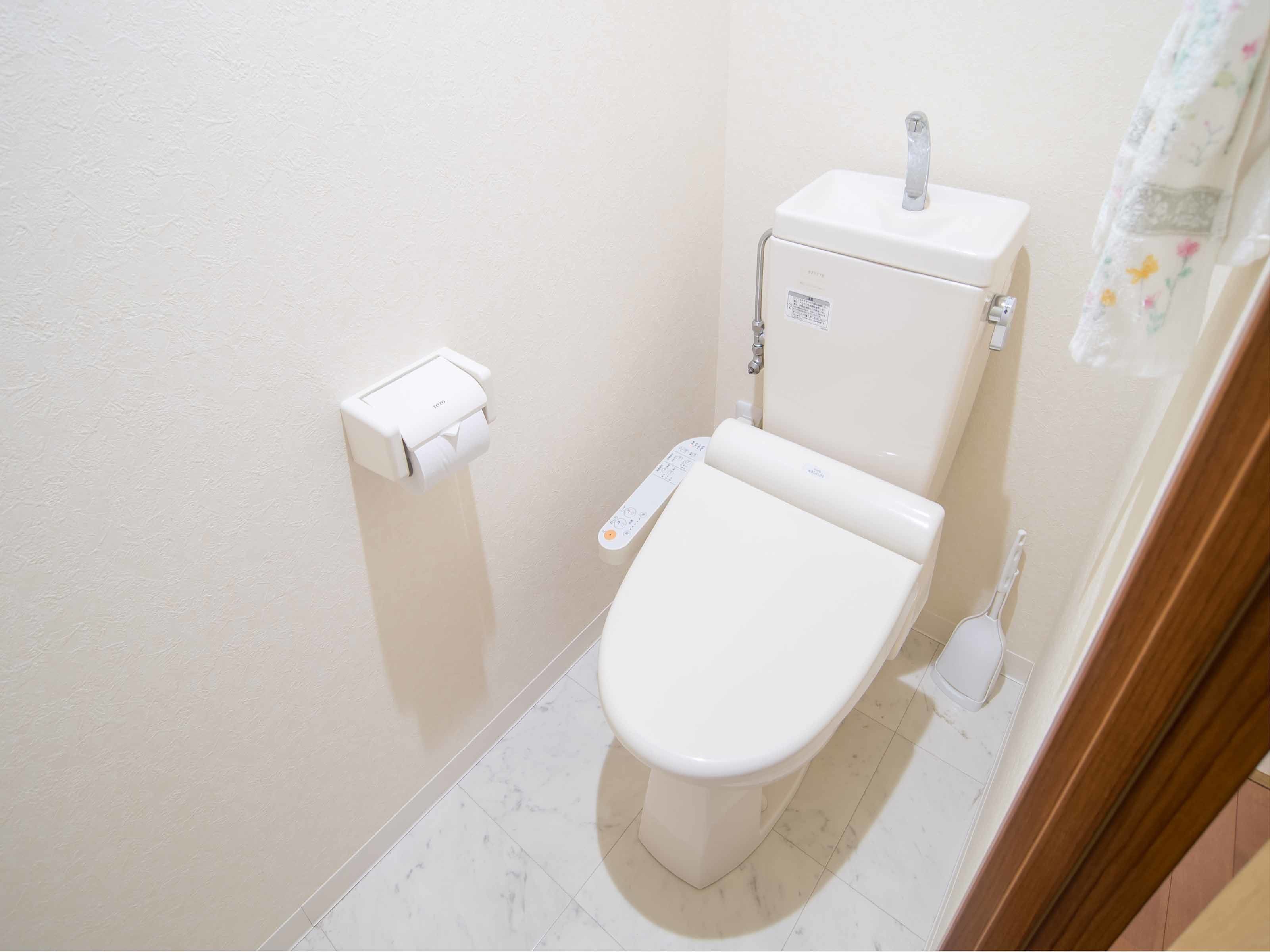 Un baño pequeño y funcional con inodoro, dispensador de toallas de papel y botón de descarga.