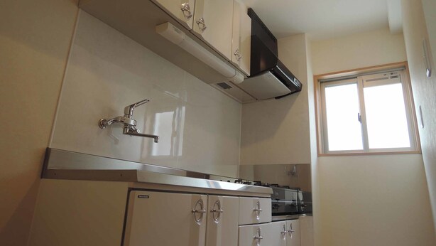 Een kleine keuken met witte kastjes, een roestvrijstalen spoelbak en een inbouwfornuis.