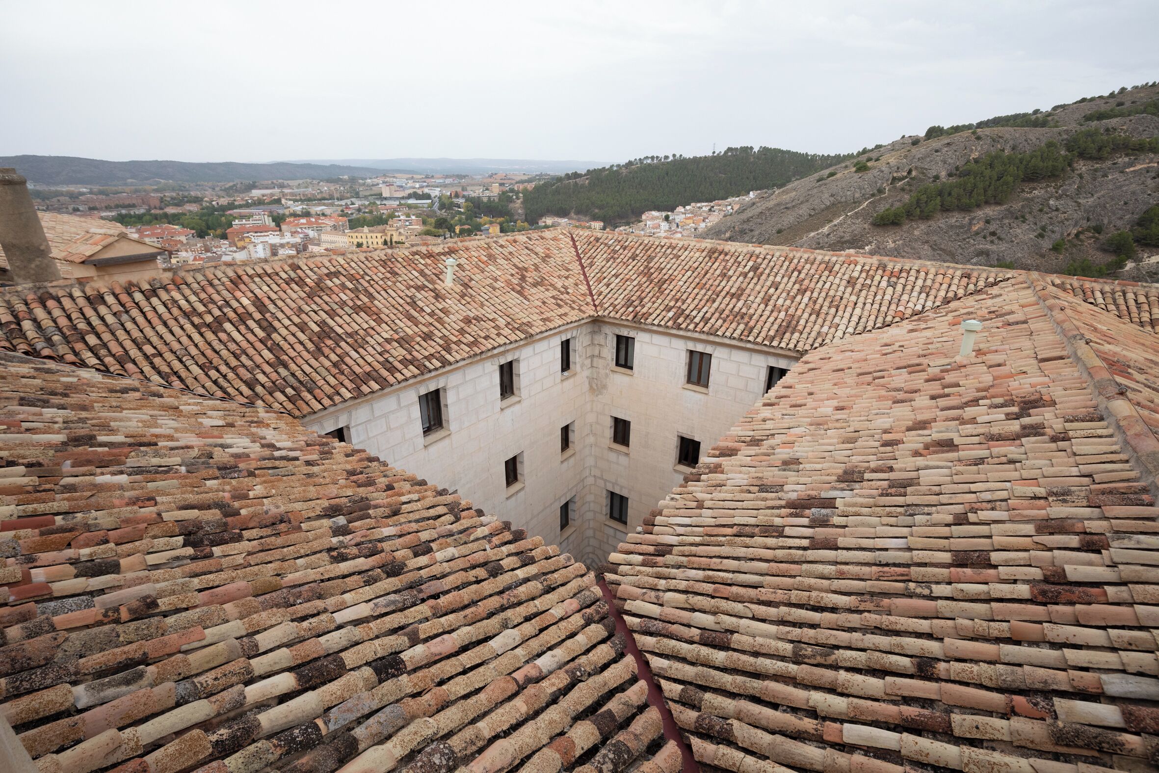 Vista de techos de tejas color terracota con un patio central y edificios circundantes.
