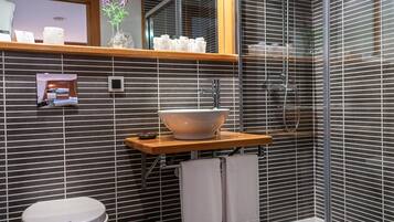 A modern bathroom with a large sink, a toilet, and a shower.