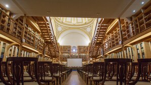 A library with rows of wooden chairs and bookshelves. - Hospedería del Seminario (Cuenca)