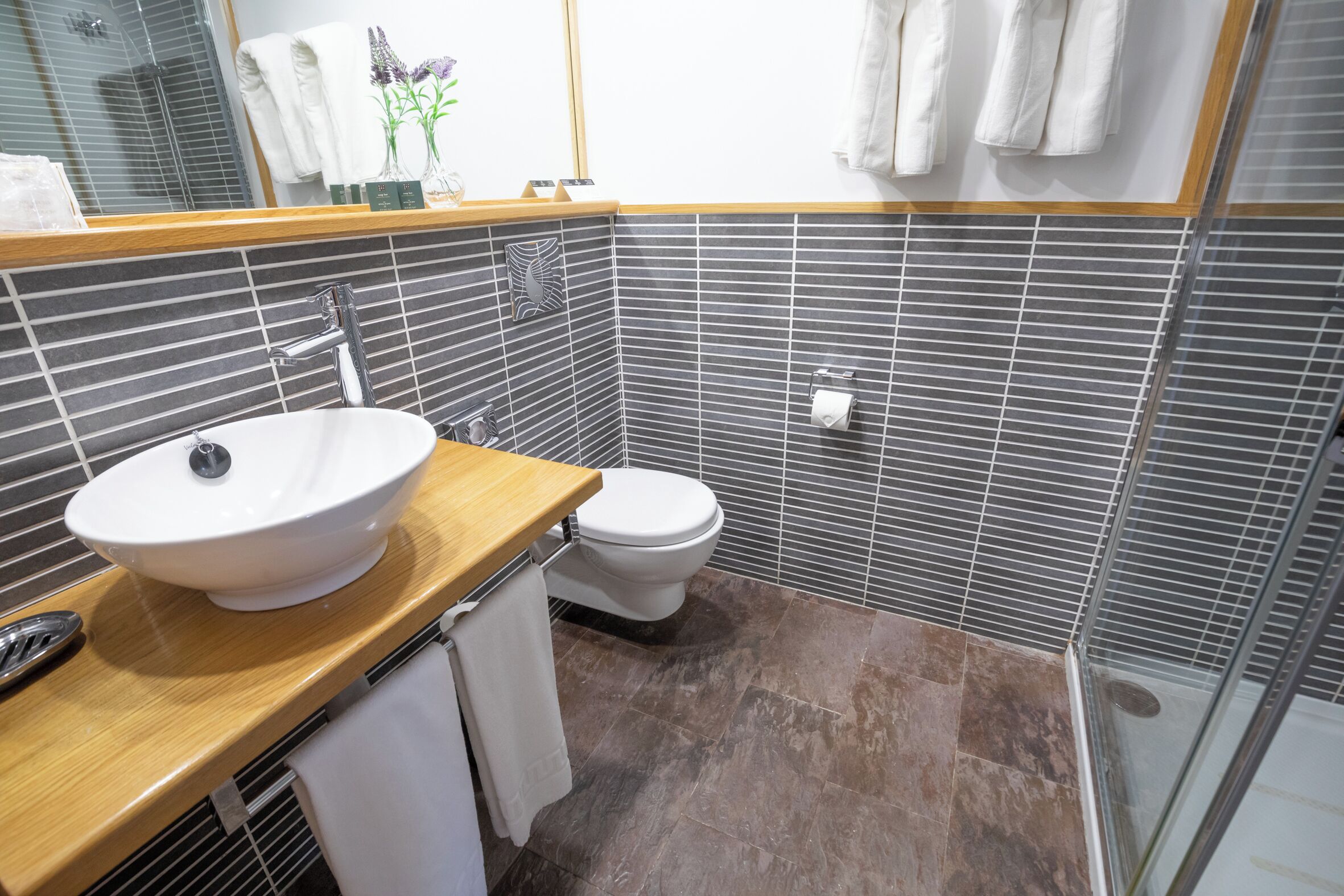 Une salle de bain moderne avec un meuble-lavabo en bois, un lavabo blanc et des toilettes.