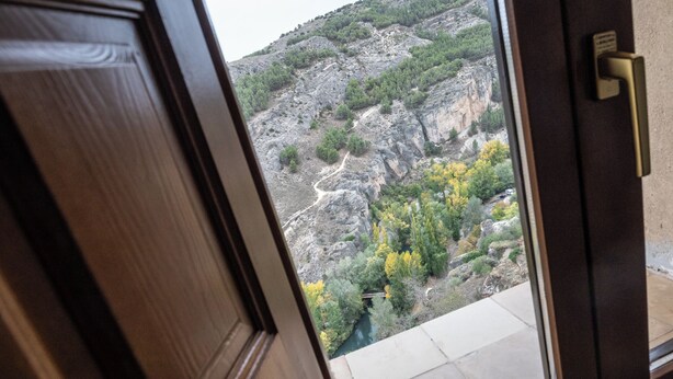 A view through a wooden door of a mountainous landscape with a river and trees. - Hospedería del Seminario (Cuenca)