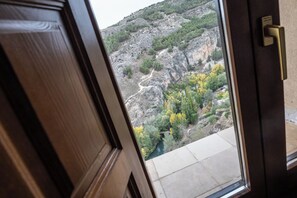 A view through a wooden door of a mountainous landscape with a river and trees. - Hospedería del Seminario (Cuenca)