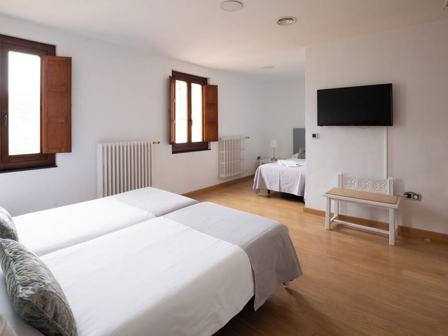 Une chambre d’hôtel avec deux lits, un banc, une télévision et un radiateur.