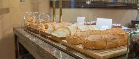 Una vitrina de panadería con panes y pasteles diversos.