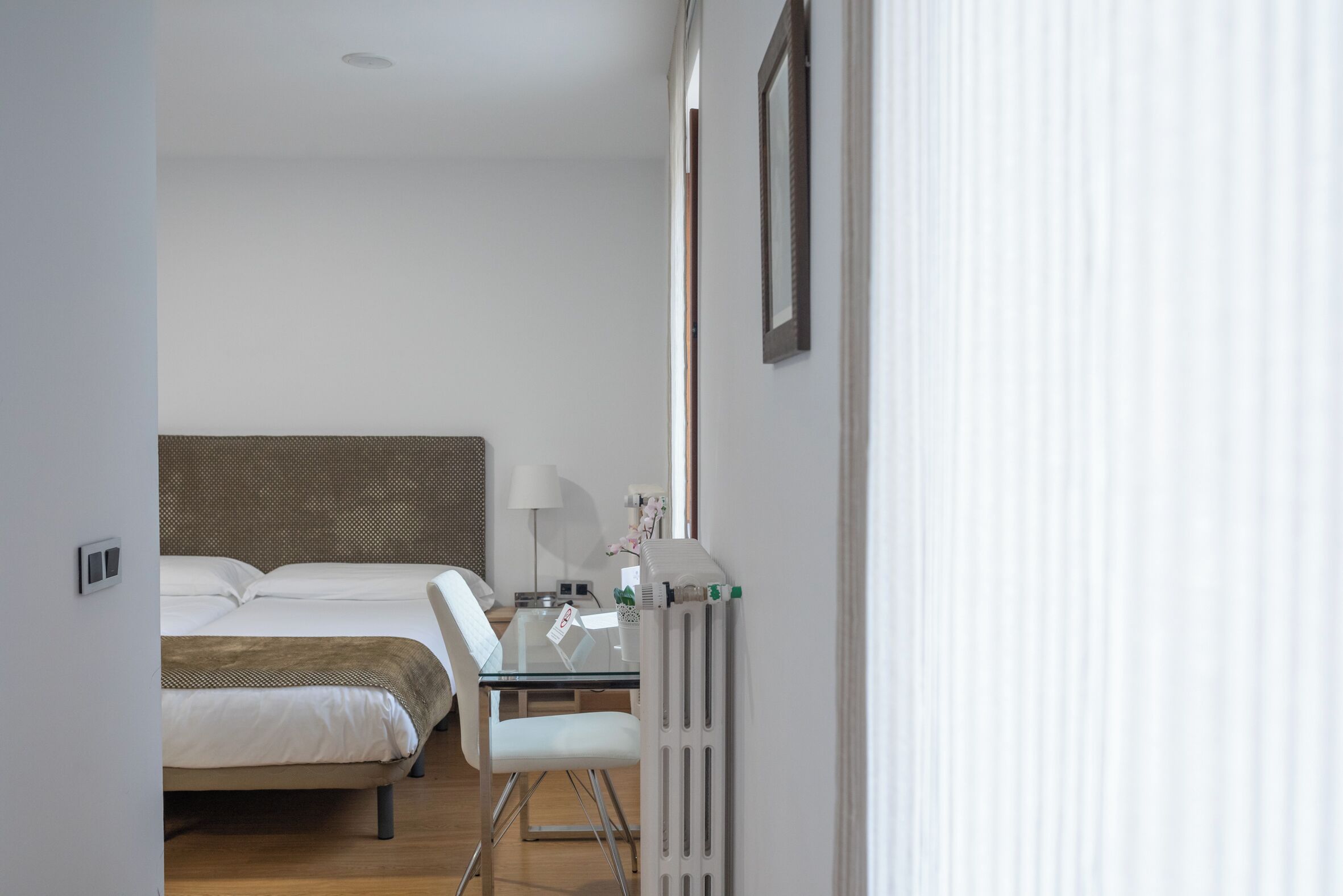 Un dormitorio con cama, mesita de noche, lámpara y un radiador.