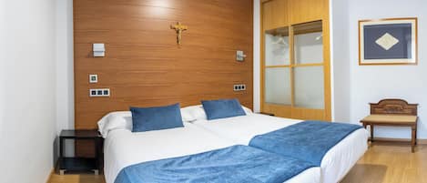 A double bed with a wooden headboard, a nightstand, a wooden wardrobe, and a framed picture on the wall.