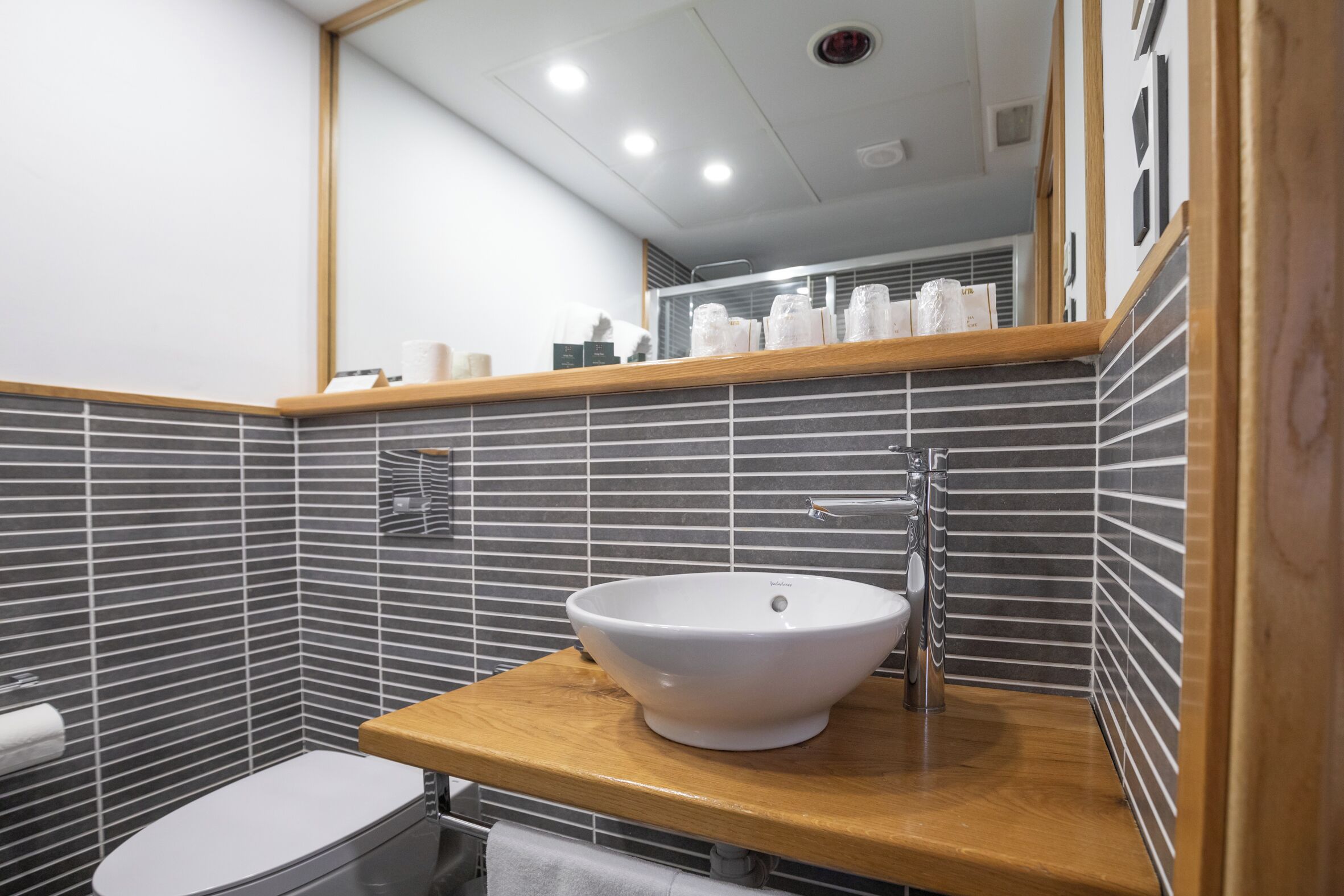 Een moderne badkamer met een houten wastafelmeubel, een witte wastafel en een toilet.