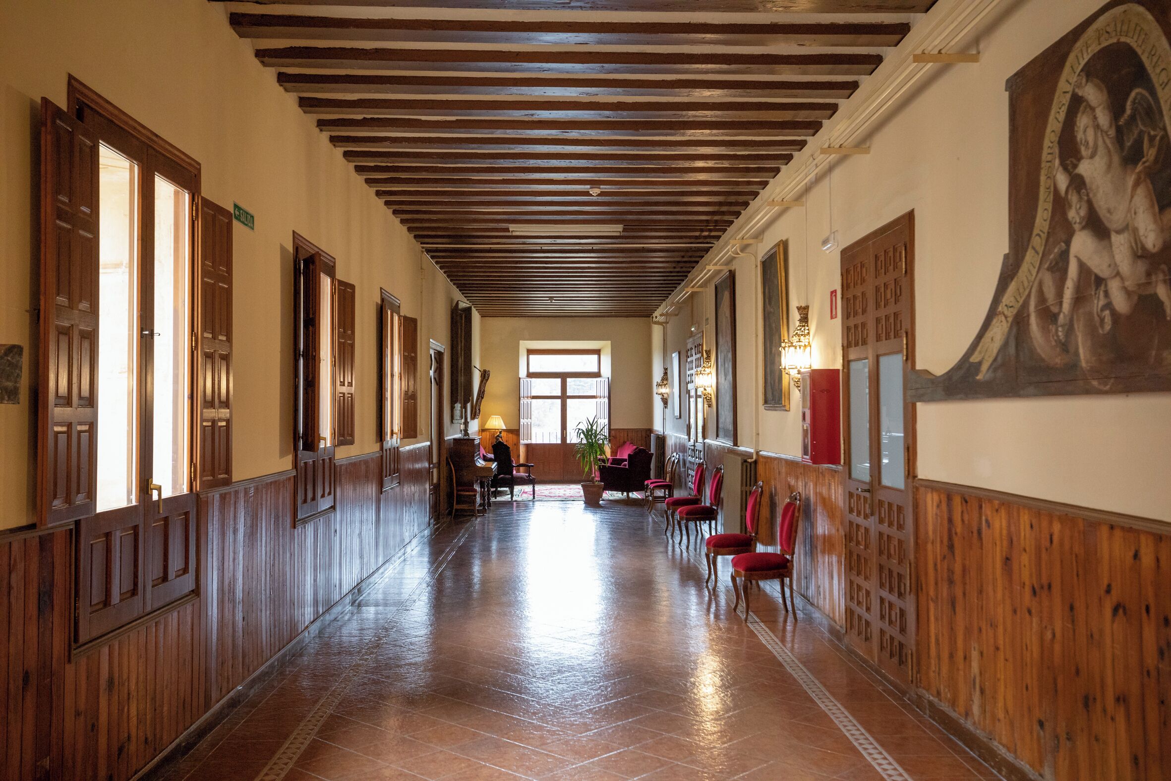 A hallway with wooden paneling, a tiled floor, and a large mural on the wall.