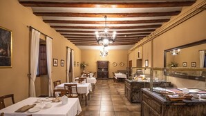 A dining area with tables set for service, a buffet counter, and a wooden ceiling with exposed beams. - Hospedería del Seminario (Cuenca)