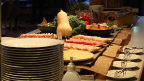 Een buffetopstelling met diverse gerechten en uitzicht op zee door grote ramen.
