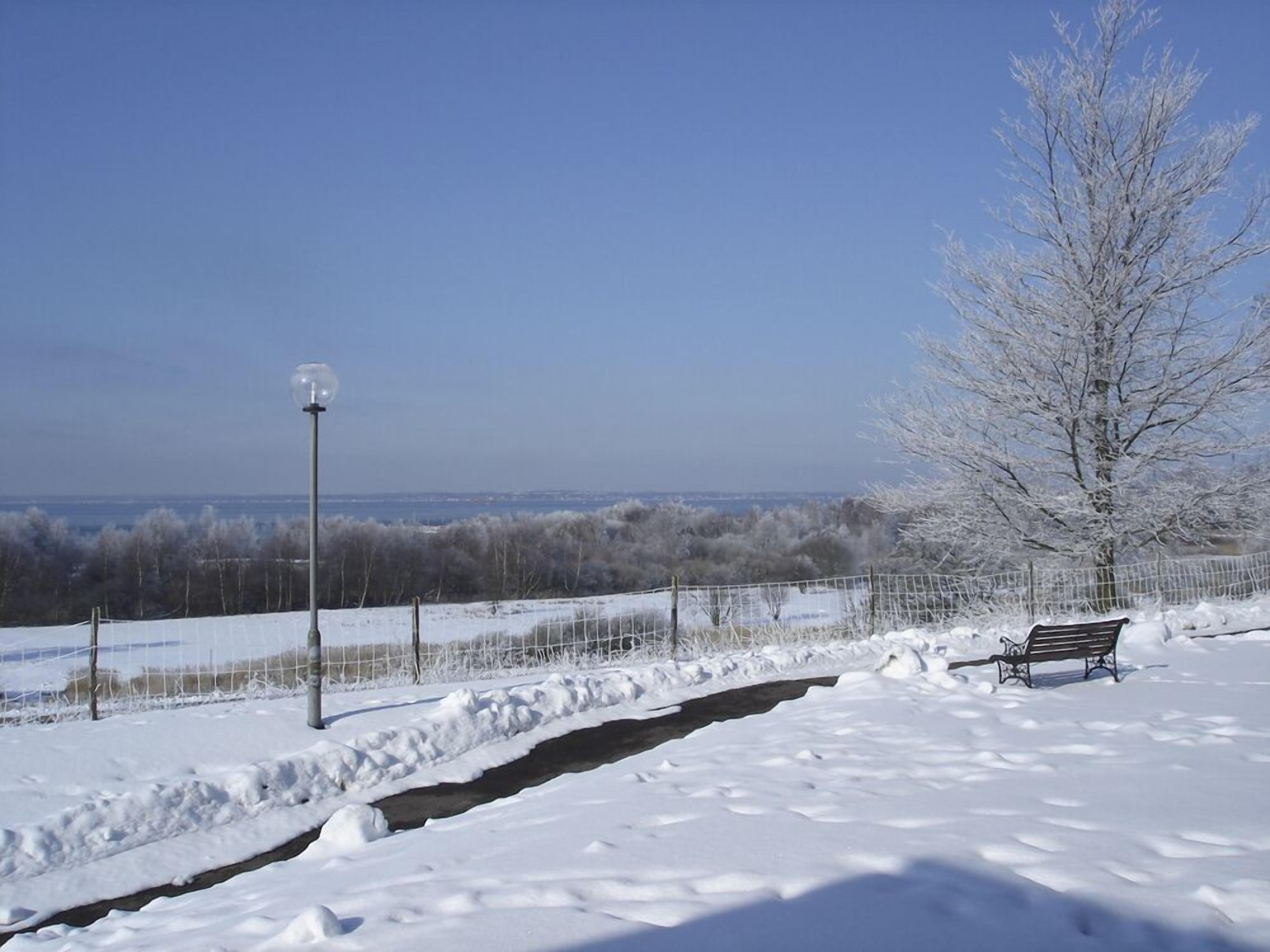 A bench in a snowy landscape with a clear view of the horizon.