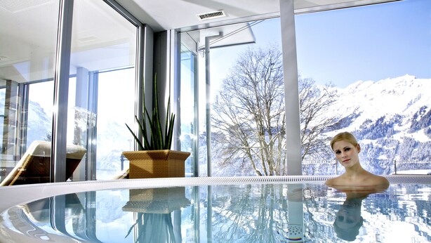 Una piscina interior moderna con vistas despejadas a montañas nevadas.
