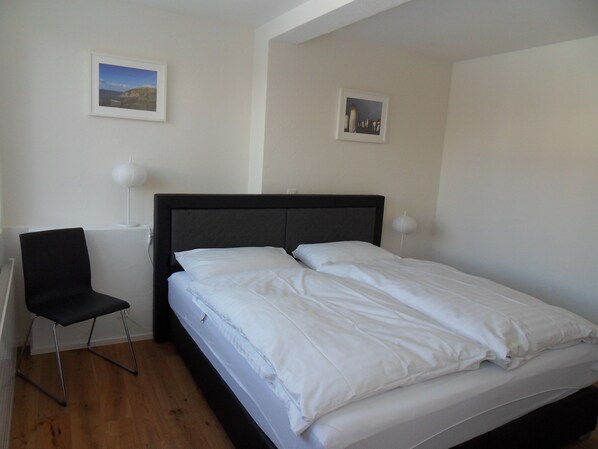 A bedroom with a bed, a chair, and two wall-mounted lamps. - Apartement Silverpeak (Lauterbrunnen)