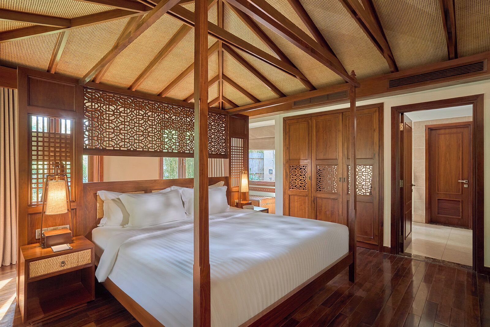 A spacious bedroom with a large bed, wooden headboard, and a ceiling with a woven design.
