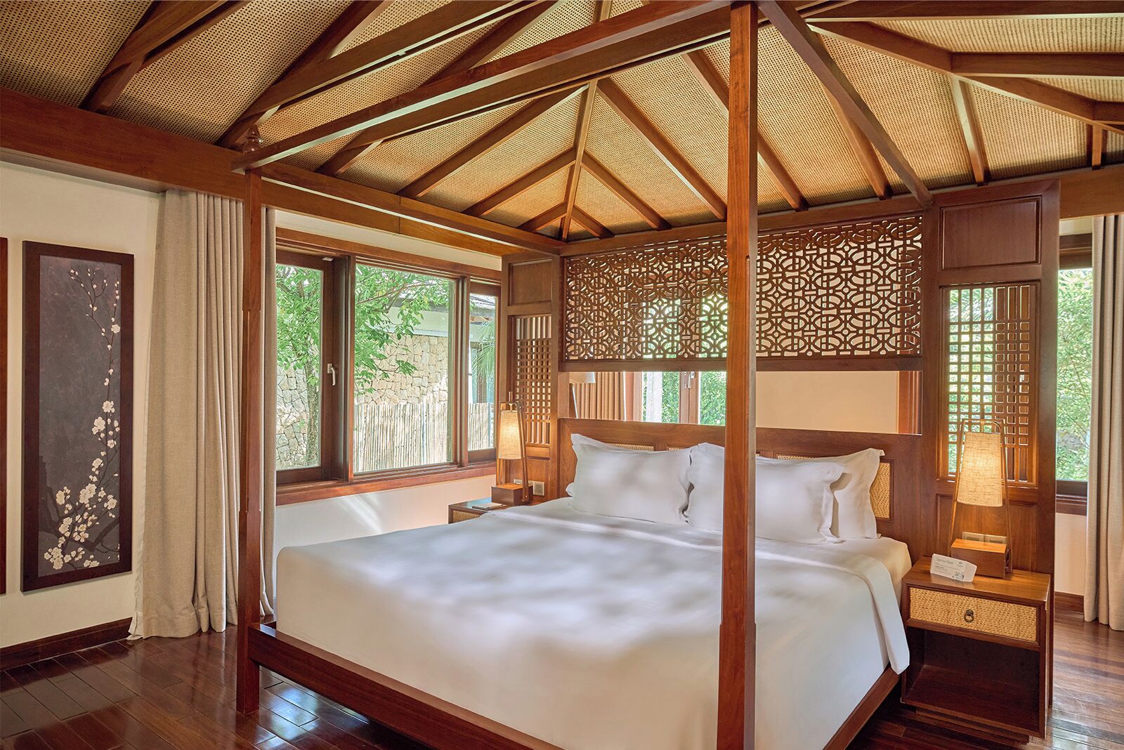 Un lit à baldaquin avec un plafond en bois et une vue sur la verdure environnante.