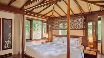 Un lit à baldaquin avec un plafond en bois et une vue sur la verdure environnante.