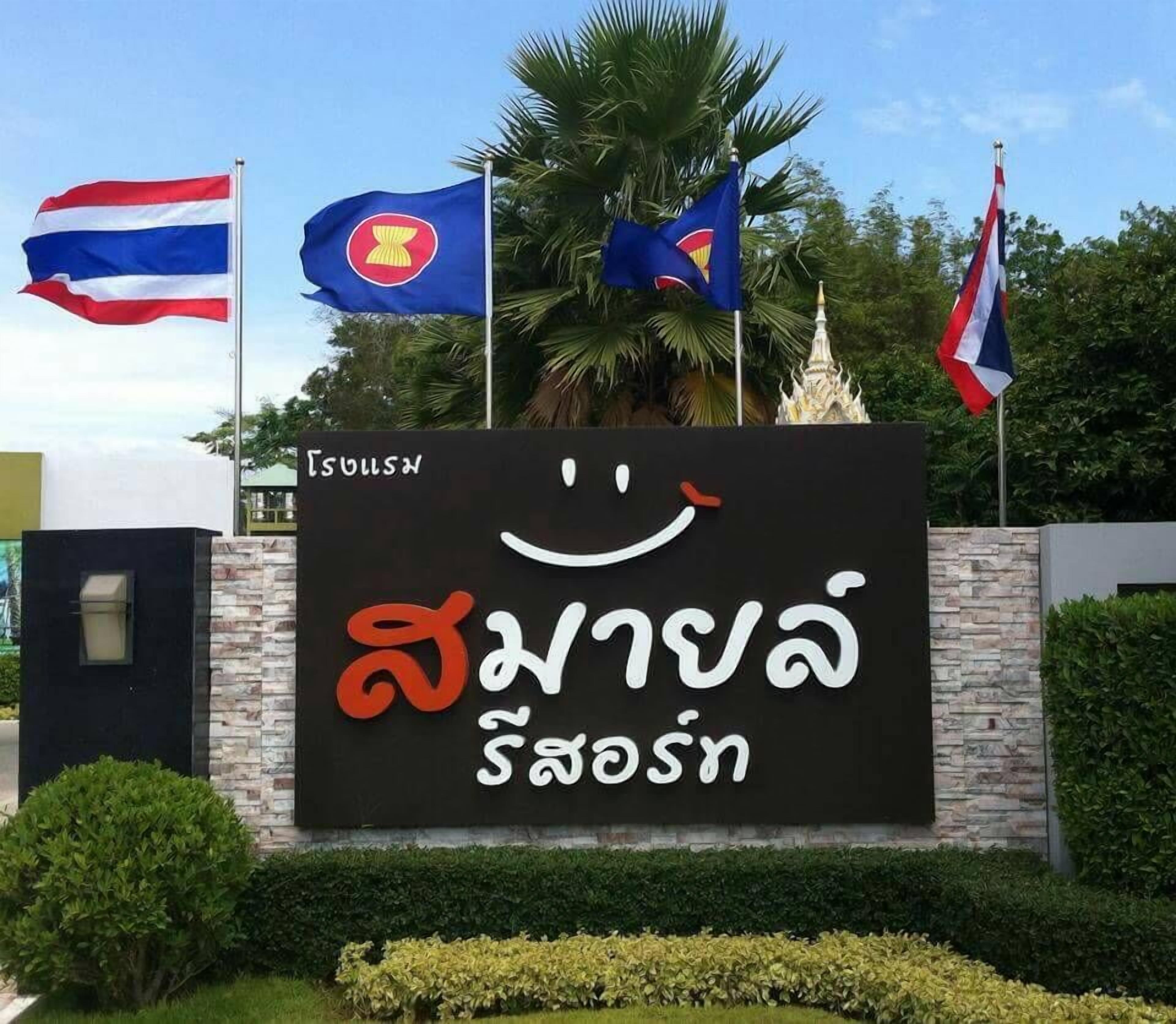Un letrero con escritura tailandesa y banderas de Tailandia, Laos y Camboya.
